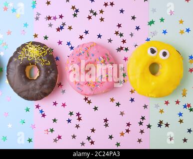 Runde Donuts mit verschiedenen Füllungen und Streuseln auf eine abstrakte Farbe Hintergrund mit festlichen Dekor Stockfoto