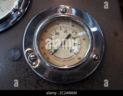 Nahaufnahme eines alten runden Metalltemperaturmessers mit dem Zählerstand in Fahrenheit und Celsius mit einer glänzenden Chrom-Surround-m Stockfoto