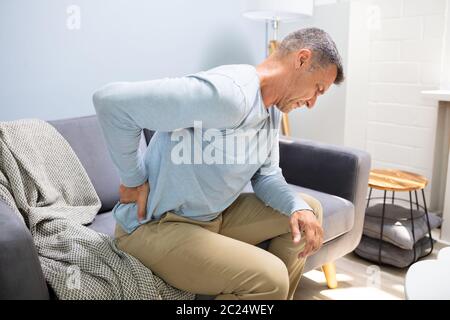 Mann auf dem Sofa leiden unter Rückenschmerzen zu Hause Stockfoto