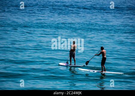 Zwei Männer auf Surfbrettern paddeln im Meer in St. Ives, Cornwall. Stockfoto