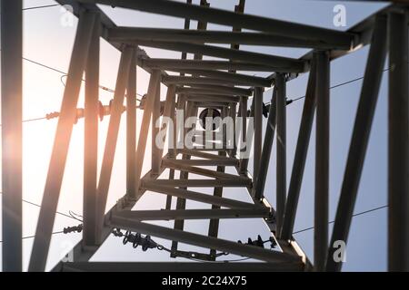 Ansicht von unten Hochspannungsturm in Sonnenuntergang. Tageslicht blauer Himmel Hintergrund Hochtechnologie, Hintergrund Technologie Konzept. Stockfoto