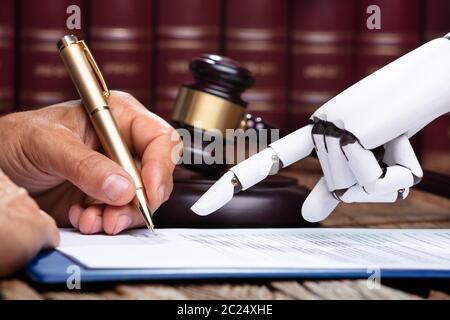 Roboterhand Unterstützung der Person, die für die Unterzeichnung dieses Dokuments reflektierende Schreibtisch Im Gerichtssaal Stockfoto
