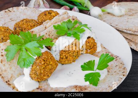 Kichererbse Falafel mit Minze-Dressing und libanesische Brot, frische Kräuter obenauf Stockfoto