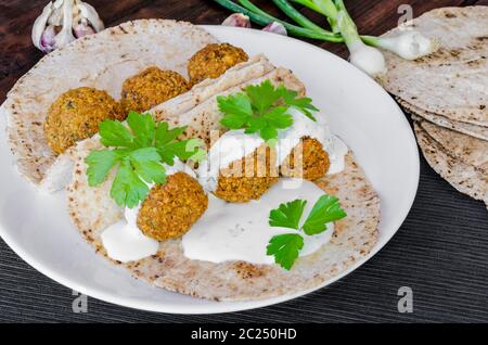 Kichererbse Falafel mit Minze-Dressing und libanesische Brot, frische Kräuter obenauf Stockfoto