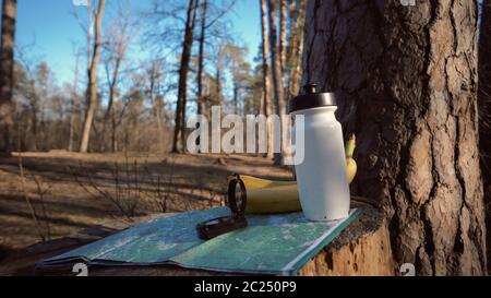 Nahaufnahme Dinge für Tourismus Reisen für Öko-Tourismus in Natur Wald. Papierkarte, Kompass und Snack-Food-Flasche Flasche mit Wasser A Stockfoto