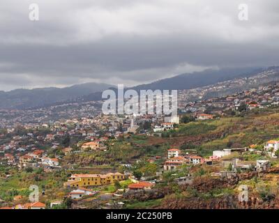 Ein Panoramablick auf funchal auf madeira zeigt kleine Bauernhöfe und Landwirtschaft mit Gebäuden der Stadt gegen ferne bewölkte mou Stockfoto