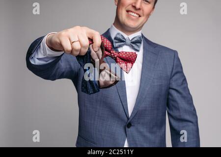 Lächelnd Mann insmart Anzug Fliege in der Hand halten. Stockfoto