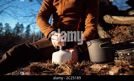 Das Thema des Tourismus ist Wandern und Reisen in der Natur. Hände EIN kaukasischer Mann verwendet Ausrüstung, um Essen draußen zu kochen. Ein Tourist ins Stockfoto