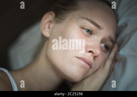 Eine unglückliche, elende Person, die auf ihrem Kissen liegt und unter tiefer Depression leidet. Stockfoto