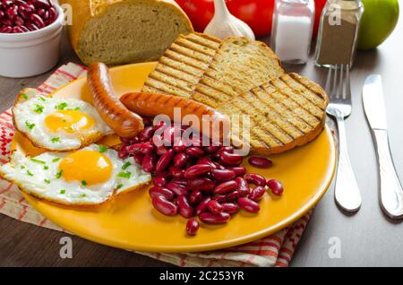 Englisches Frühstück - Knoblauch-Toast, Spiegelei, Bohnen und Bohnenkraut Wurst Stockfoto