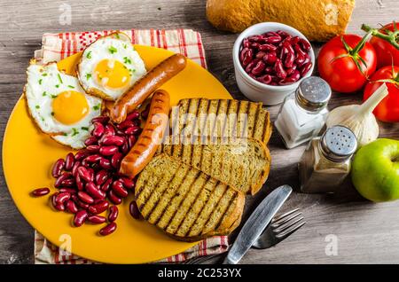 Englisches Frühstück - Knoblauch-Toast, Spiegelei, Bohnen und Bohnenkraut Wurst Stockfoto