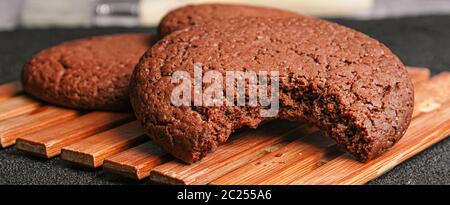 Schokolade Haferflocken Cookies drei Stücke ein bissen liegt auf einem Bambusplatte auf schwarzem Beton. Close up Stockfoto