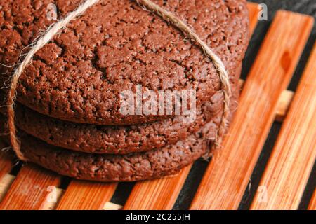 Schokolade Haferflocken Cookies mit einem Seil gebunden liegen auf einem Bambusplatte auf schwarzem Beton. Close up Stockfoto