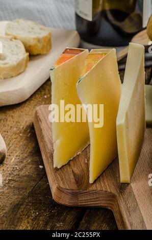 Reifen Käsesorten mit knusprigem Baguette und Wein, Holzplatte Stockfoto