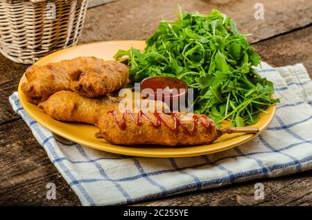 Corndog mit frischem Rucola-Salat und feuerverzinkten, Holztisch Stockfoto