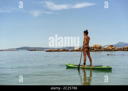 Frau, die Wassersport von Paddelsurfen im Meer macht Stockfoto