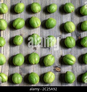 Junge grüne Früchte der Walnüsse liegen in den Zeilen auf einem grauen Hintergrund Holz Stockfoto