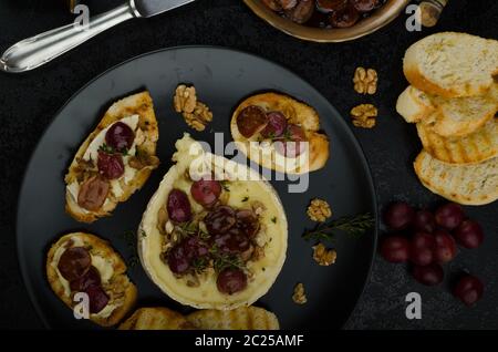 Brie Käse gebacken mit Nüssen und Trauben, leckere und knusprige Baguette und Bio-Kräuter, Reduzierung von Zucker, Nüssen und Balsamico-Essig Stockfoto