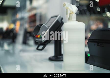 Desinfektionsflasche im Geschäft für Kunden in der Nähe des kontaktlosen Zahlungsterminals, Nahaufnahme. Stockfoto