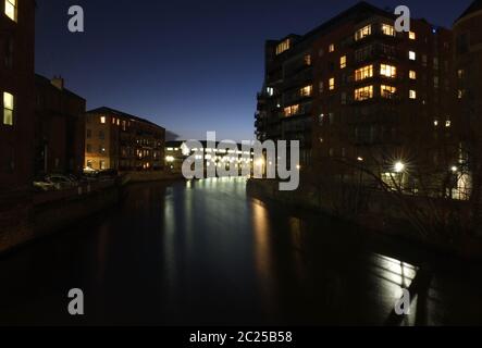 Der Fluss aire in leeds bei Nacht mit beleuchteten Fenstern in Wohngebäuden und Büros im Wasser reflektiert Stockfoto