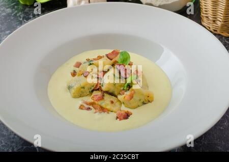 Spinat-Gnocchi mit Parmesan-Sauce, garniert mit Speck, reinigen dienen, Zutaten im Hintergrund Stockfoto