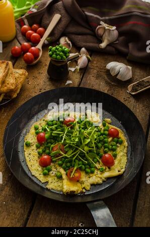 Gesunden Omelette mit Gemüse - Erbsen und Sonnenblumen Microgreens toast Cherry-Tomaten Stockfoto