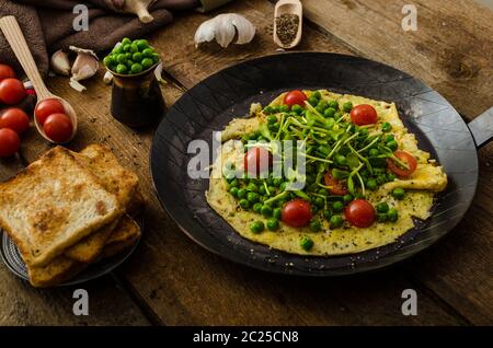 Gesunden Omelette mit Gemüse - Erbsen und Sonnenblumen Microgreens toast Cherry-Tomaten Stockfoto