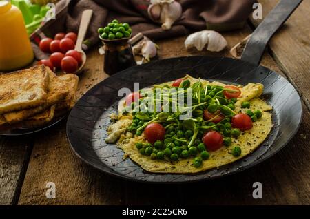 Gesunden Omelette mit Gemüse - Erbsen und Sonnenblumen Microgreens toast Cherry-Tomaten Stockfoto