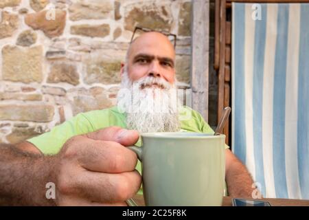 Bärtiger Mann Hände auf Kaffeebecher Stockfoto