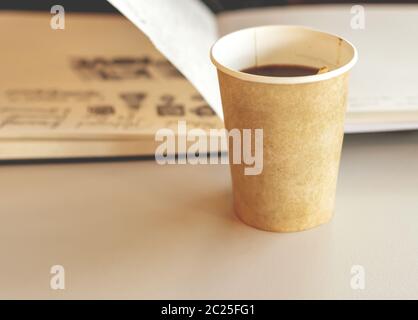 Kaffee in einem recycelbaren Papier Einweg-Glas mit einem offenen Notizbuch im Hintergrund Stockfoto