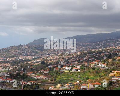 Luftbild Stadtbild Blick auf den Stadtrand von funchal in Madeira mit Bauernhöfen und Häusern mit Bergen und wolkenbehdem Himmel in der Ferne Stockfoto