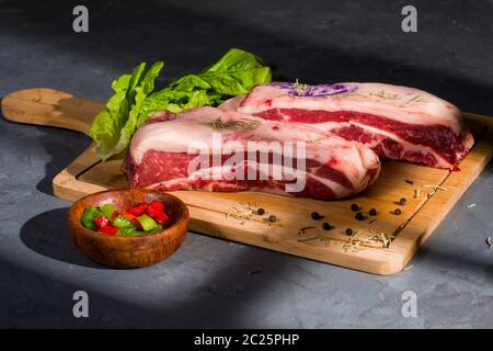 Argentinisches rohes Fleisch auf einem Holztisch mit grünem und re Pfeffer Stockfoto