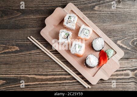 Drei verschiedene Arten von japanischen Rollen mit Wasabi und Ingwer auf Bambus tablett auf schönen hölzernen Hintergrund Stockfoto