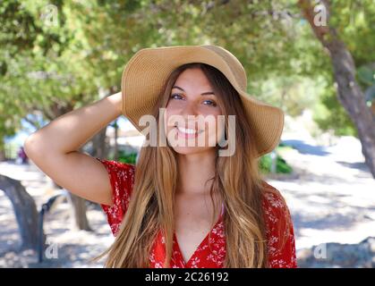 Porträt einer wunderschönen lächelnde Mädchen das Tragen der roten Kleid und Strohhut auf Kamera Stockfoto