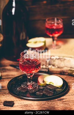 Hausgemachte rote Johannisbeere nalivka und Schokolade mit in Scheiben geschnittenen Apfel auf Metall Fach Stockfoto