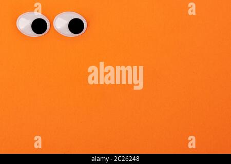 Zwei Spielzeug Augen auf orangefarbenem Hintergrund auf der Seite Stockfoto