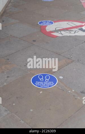 LONDON, ENGLAND - 6. JUNI 2020: Kreisförmige soziale Distanzierungsaufkleber auf dem Boden, die die physischen Entfernungsanforderungen für eine Schlange vor Moorfiel zeigen Stockfoto