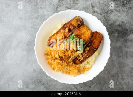 Frittierte scheiben Pangasius Fisch mit Knoblauch, mit braunem Reis serviert. Stockfoto