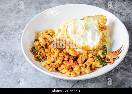 Würzig gebratener Tintenfisch mit Basilikumblättern und Chili, Sunny Side Up Ei Stockfoto