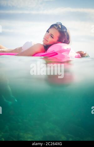Hübsche, junge Frau einen Tag am Strand genießen, Relaxen auf Luftmatratze Stockfoto