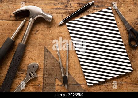 Hammer, Notizbuch, Stift, Dreiecklineal, Stift auf einem hölzernen Vintage-Hintergrund Stockfoto