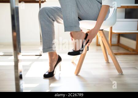 Junge Geschäftsfrau leiden unter Schmerzen im Bein, da unbequeme Schuhe im Büro Stockfoto