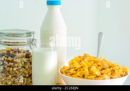 Ein Glas Milch und Milch in der Flasche leeres Etikett auf Holz Tisch in der Nähe der Schüssel Müsli mit Löffel. Calcium essen Frühstück für Kinder, bevor Sie auf Stockfoto