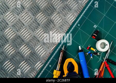 Lötwerkzeuge. Lötkolben, Spule mit Lötdraht, Schraubendreher, lötfreie isolierte Flachstecker auf Industrial Metal Riffelblech und Stockfoto