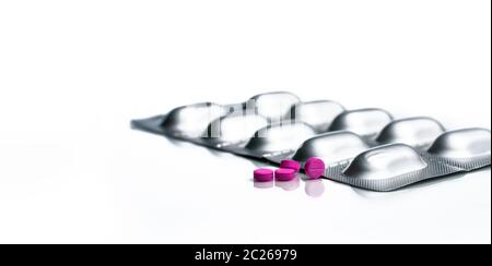 Makro-Aufnahme von kleinen rosa Tabletten Pillen und Silber Aluminiumfolie Blister Packung von Pillen auf weißem Hintergrund. Pharmaindustrie. Apotheke Droge st Stockfoto