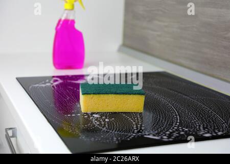 Reinigung der Induktionsherd mit einem Schwamm. Stockfoto