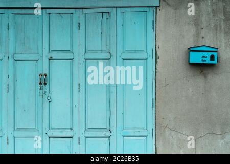 Geschlossene grüne oder blaue Tür und leeren Briefkasten auf gerissenen Beton Wand des Hauses. Altes Haus mit gecrackten Zement Wand. Vintage Haustür Abstract Stockfoto