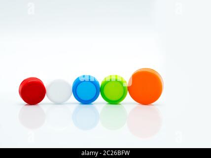 Unterschiedliche Größe von Weiß, Grün, Rot, Blau und Orange Farbe runde Schraubverschlüsse aus Kunststoff in einer Linie auf weißem Hintergrund und Kopieren. Stockfoto