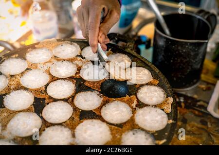Mörtel - geröstete Gebäck oder "Kanom Krok' ist für traditionelle thailändische Dessert. Frau Hand entfernen Kanom Krok von Herd durch die Löffel. Street Food in Thailand. Thai d Stockfoto