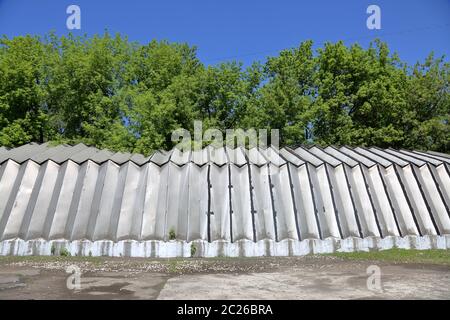 Industriehangar mit Aluminiumwänden und -Dach steht auf einem Betonfundament in der Nähe von grünen Bäumen Stockfoto